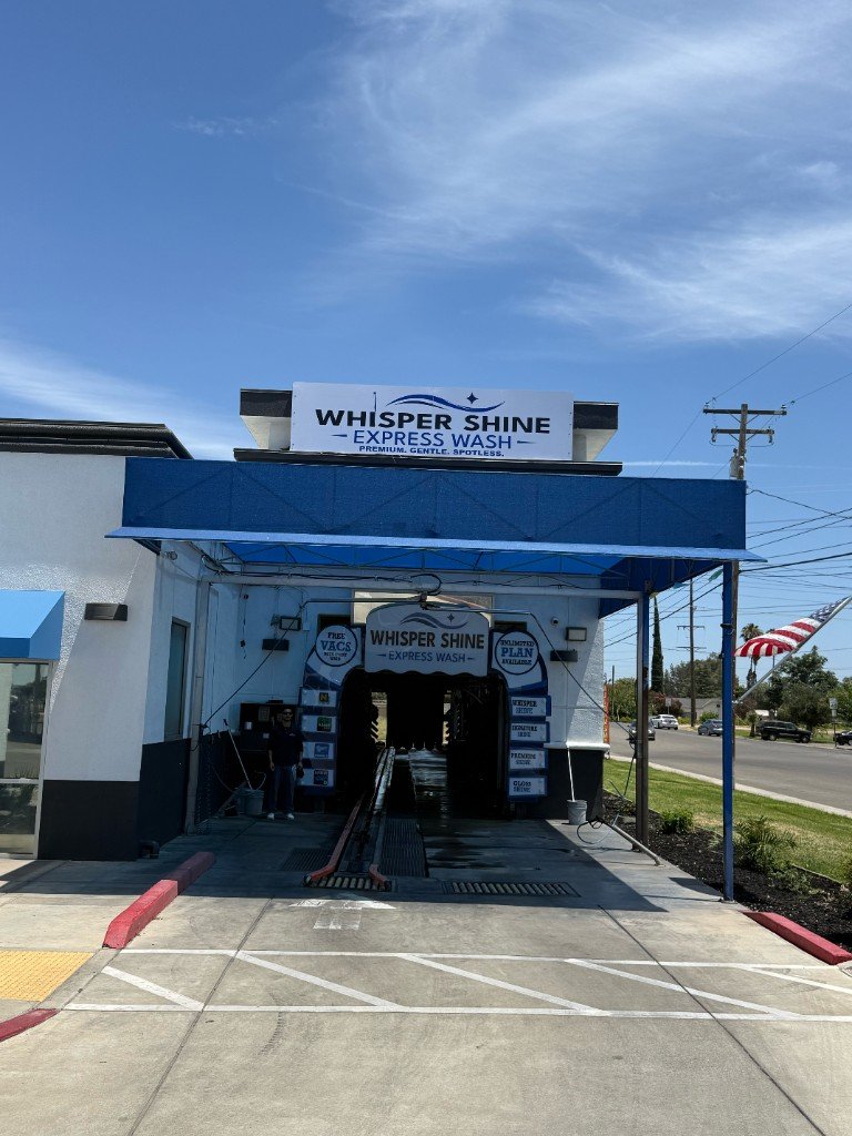 Whisper Shine Express Wash tunnel entrance with Free Vacs and Unlimited Plan signs