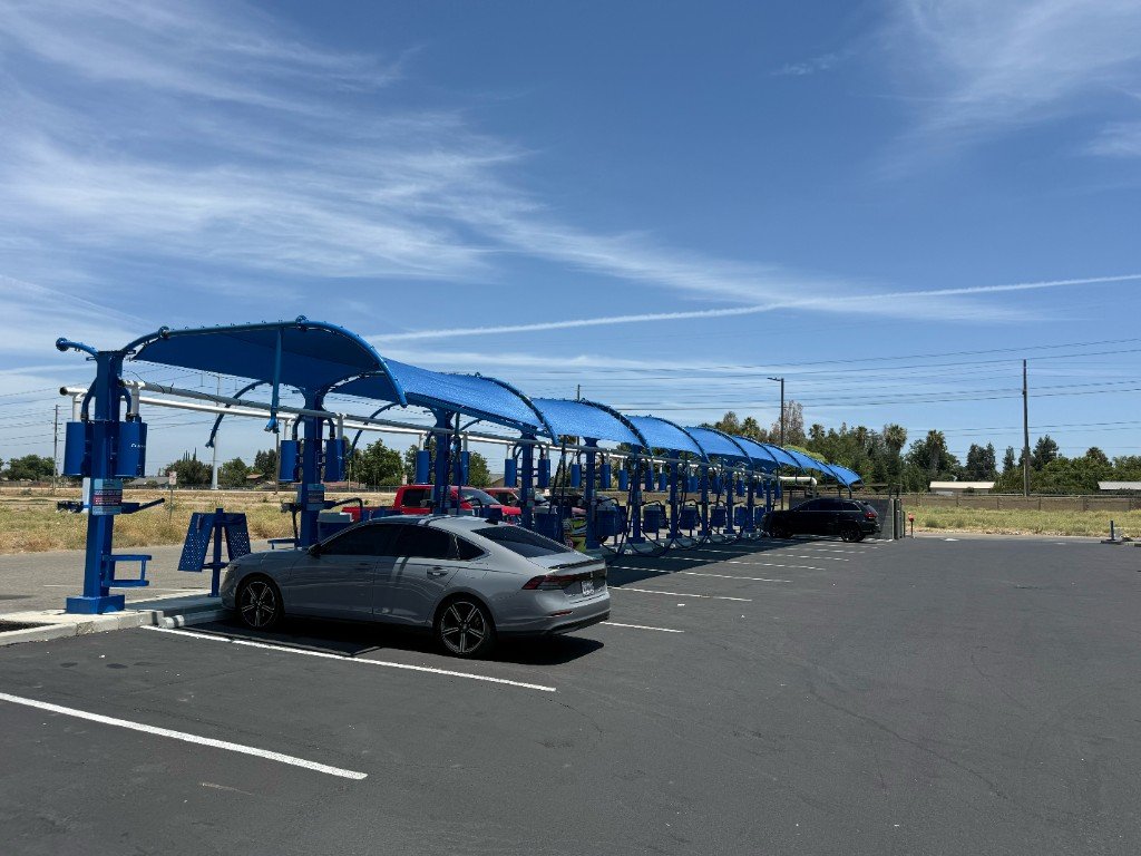 Row of blue canopy vacuum bays at Whisper Shine Express Car Wash